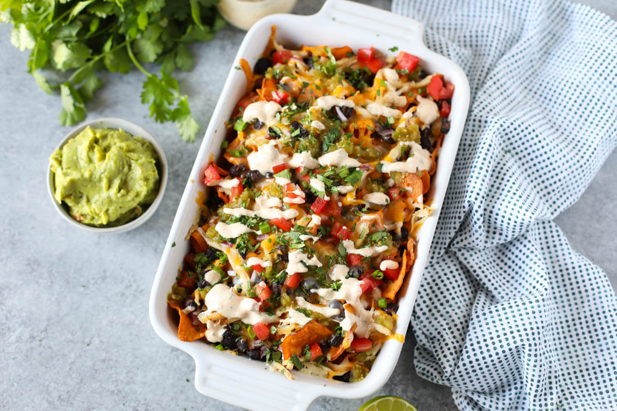 Loaded Sweet potato nachos in baking dish with a bowl of guacamole.